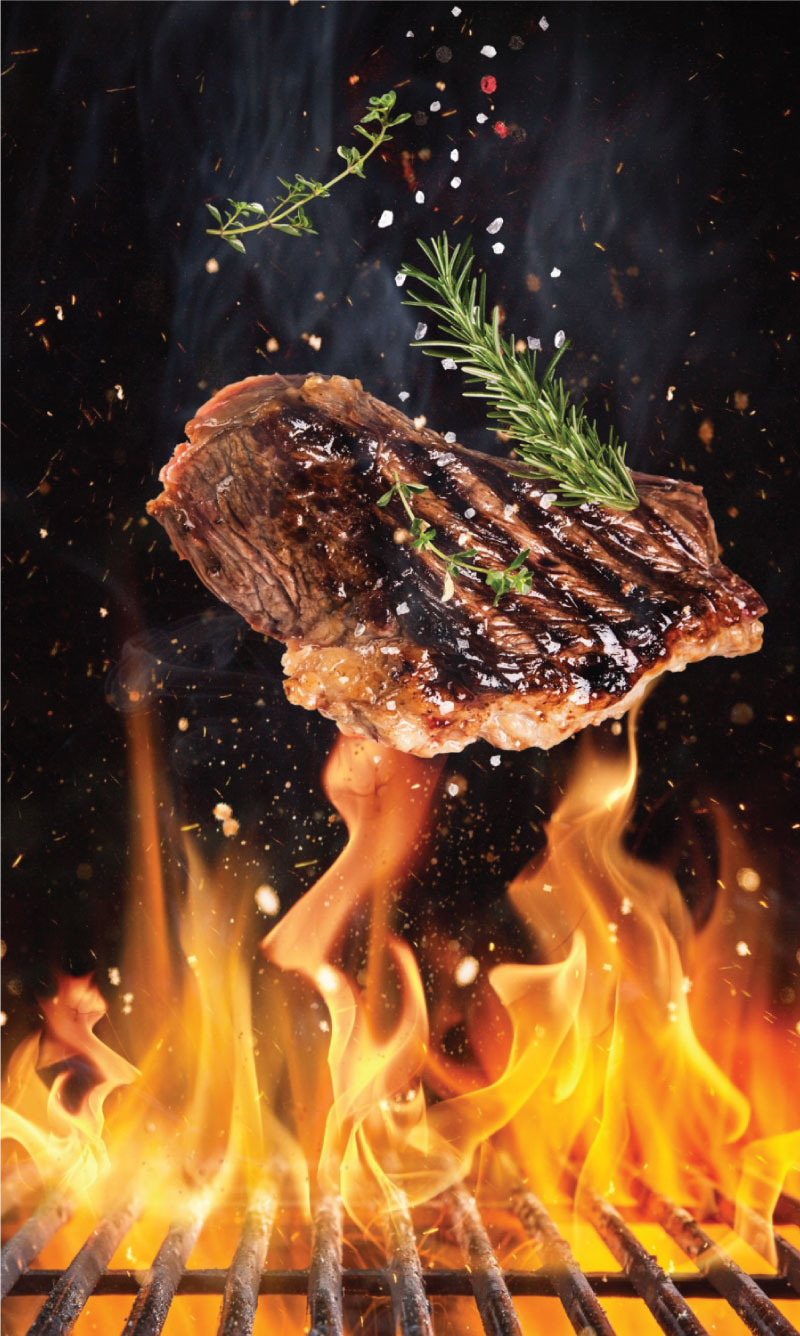 Tasty beef steaks flying above cast iron grate with fire flames.